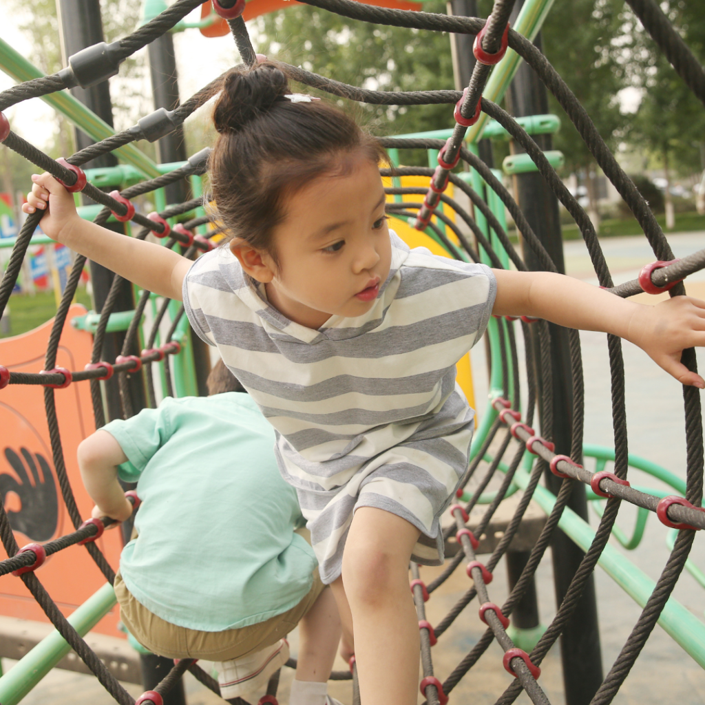 A toddler exploring a rope climbing frame in a nursery setting