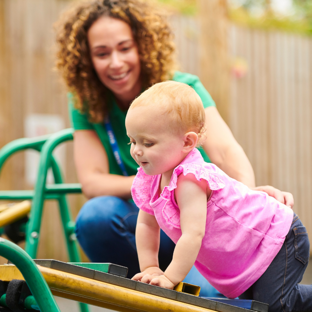 A nursery practitioner assisting a child to use playground equipment effectively