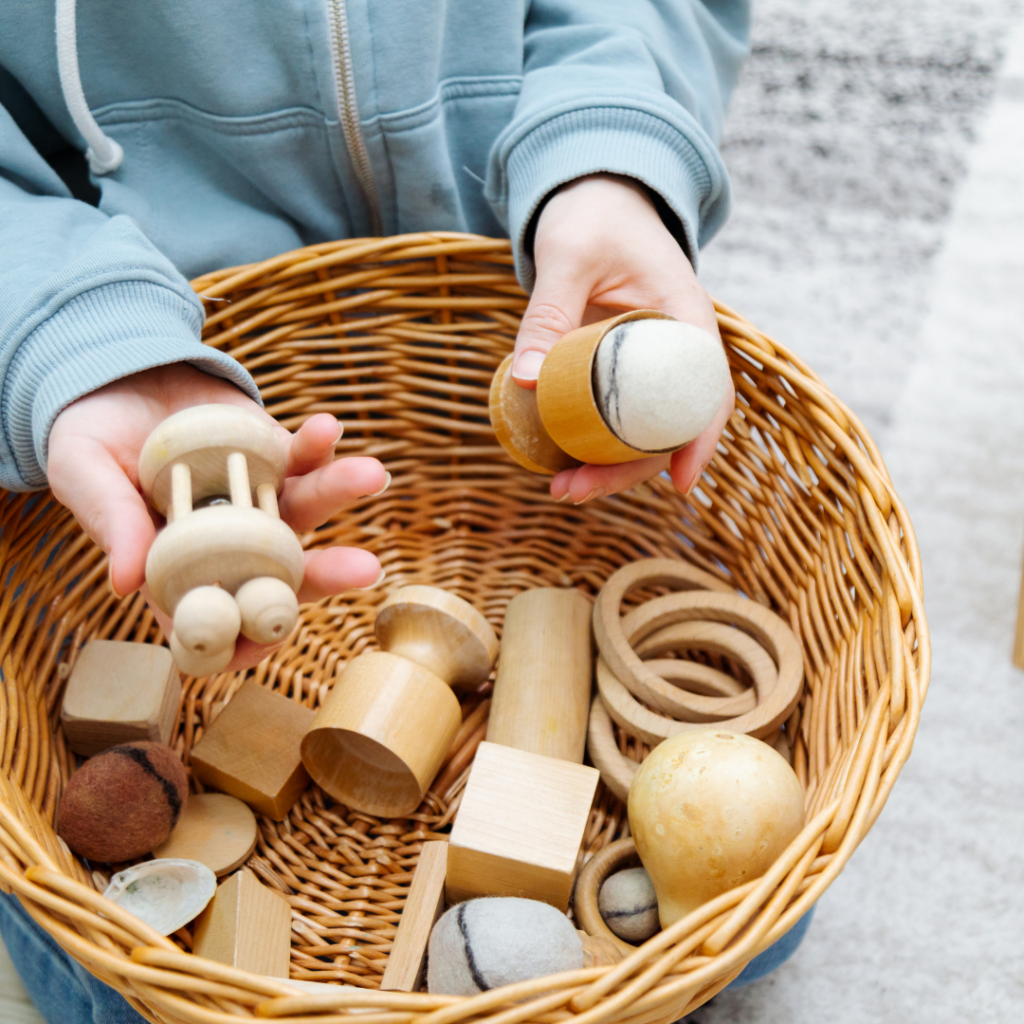 loose parts in a basket with a small child examining them in her hands.