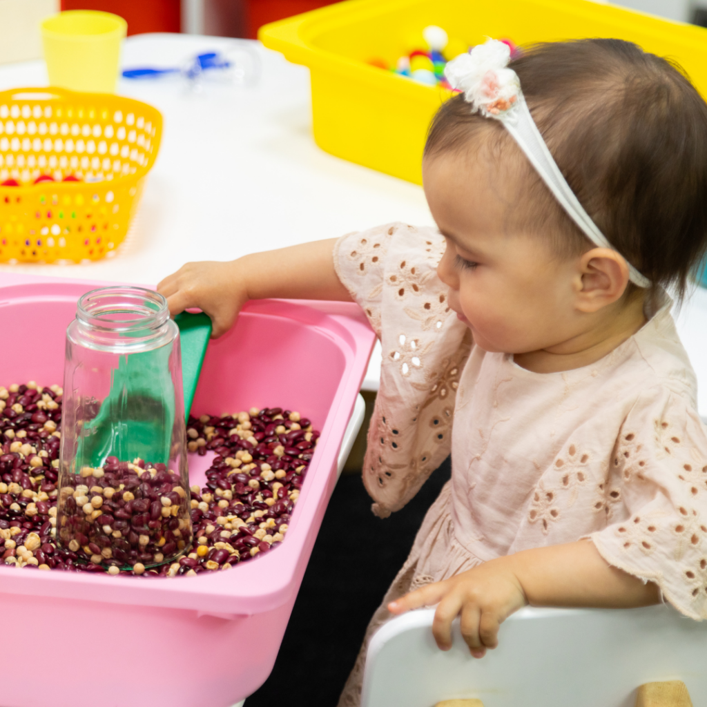 infant sorting and scooping different kinds of seeds