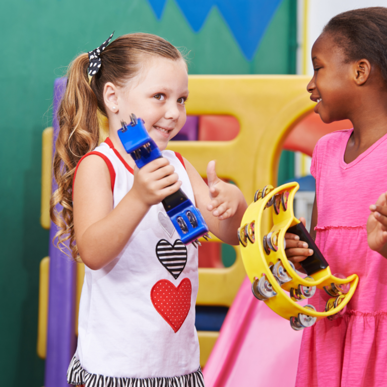 2 nursery children holding musical instruments including a tambourine