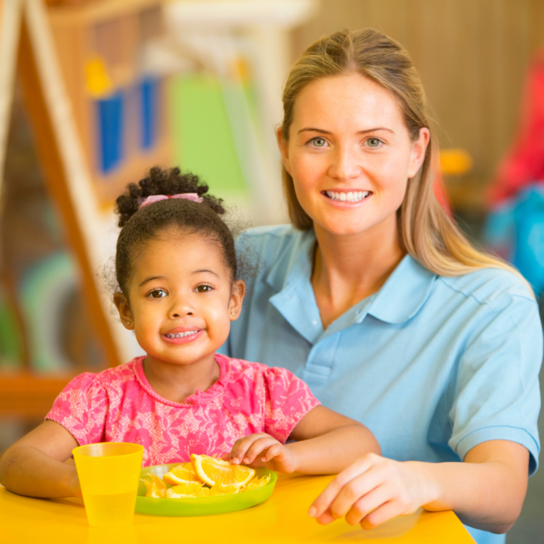 Nursery practitioner and child having a snack at the snack table.