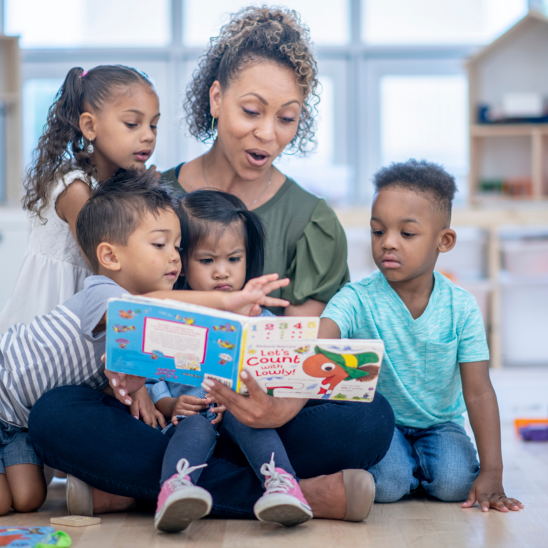 An image of a nursery teacher with several children sharing a story