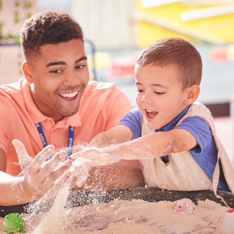 Male apprentice nursery teacher at the sand tray with a child