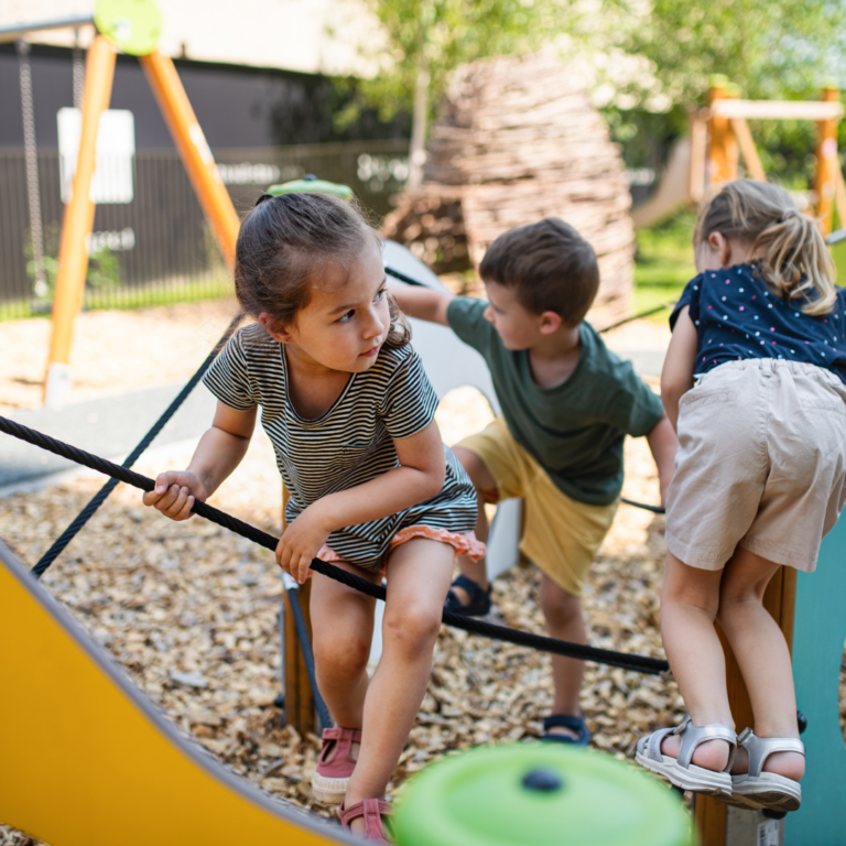 an image of preschoolers active outdoors climbing on a climbing frame